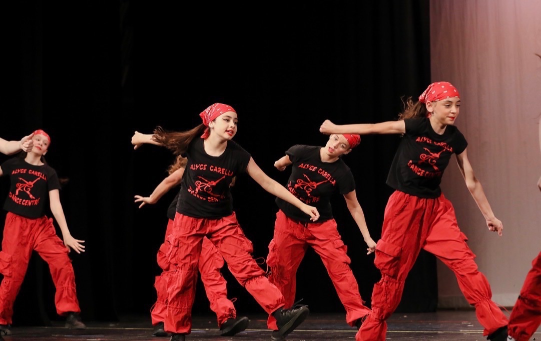 Hip-hop dancers in studio tees and red bandanas mid-routine